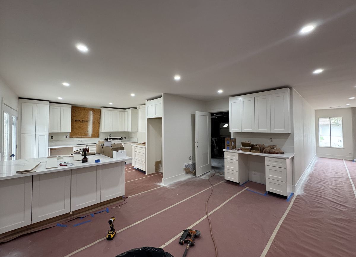 A kitchen mid-project: new shaker cabinets and counters in, floors still papered and taped